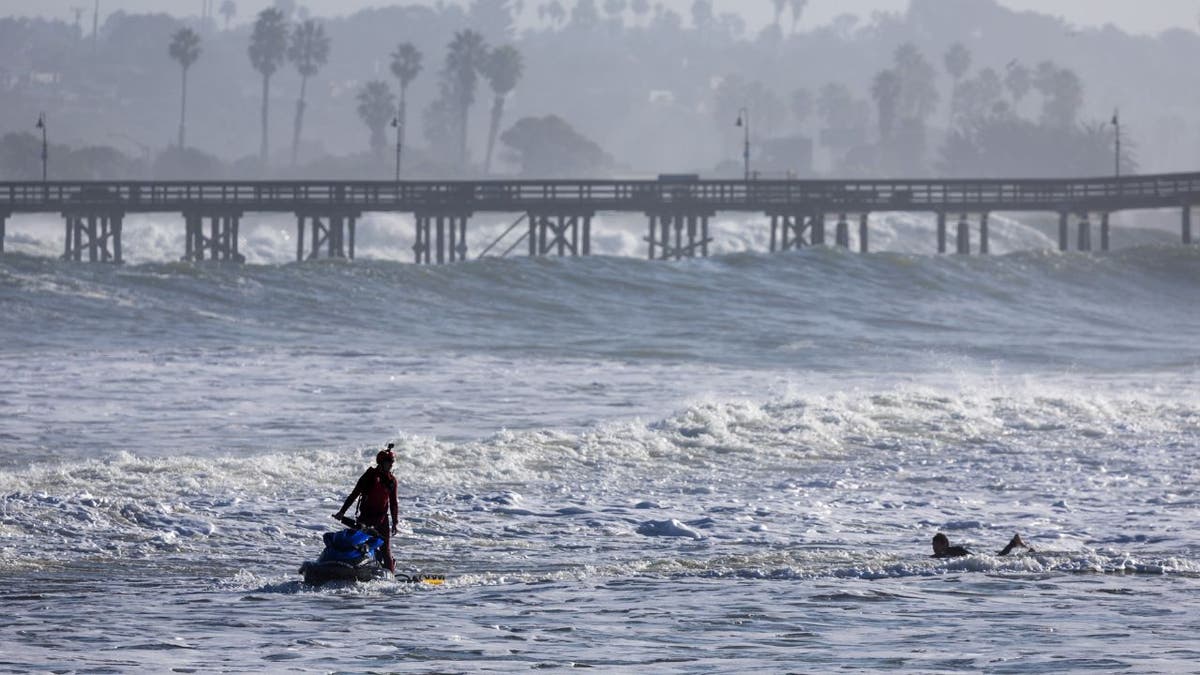 A lifeguard on a JetSki checks on a surfer 