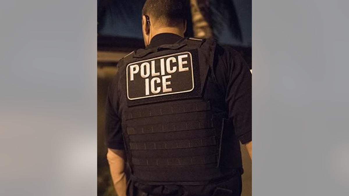 ICE officer seen from back with "Police ICE" jacket