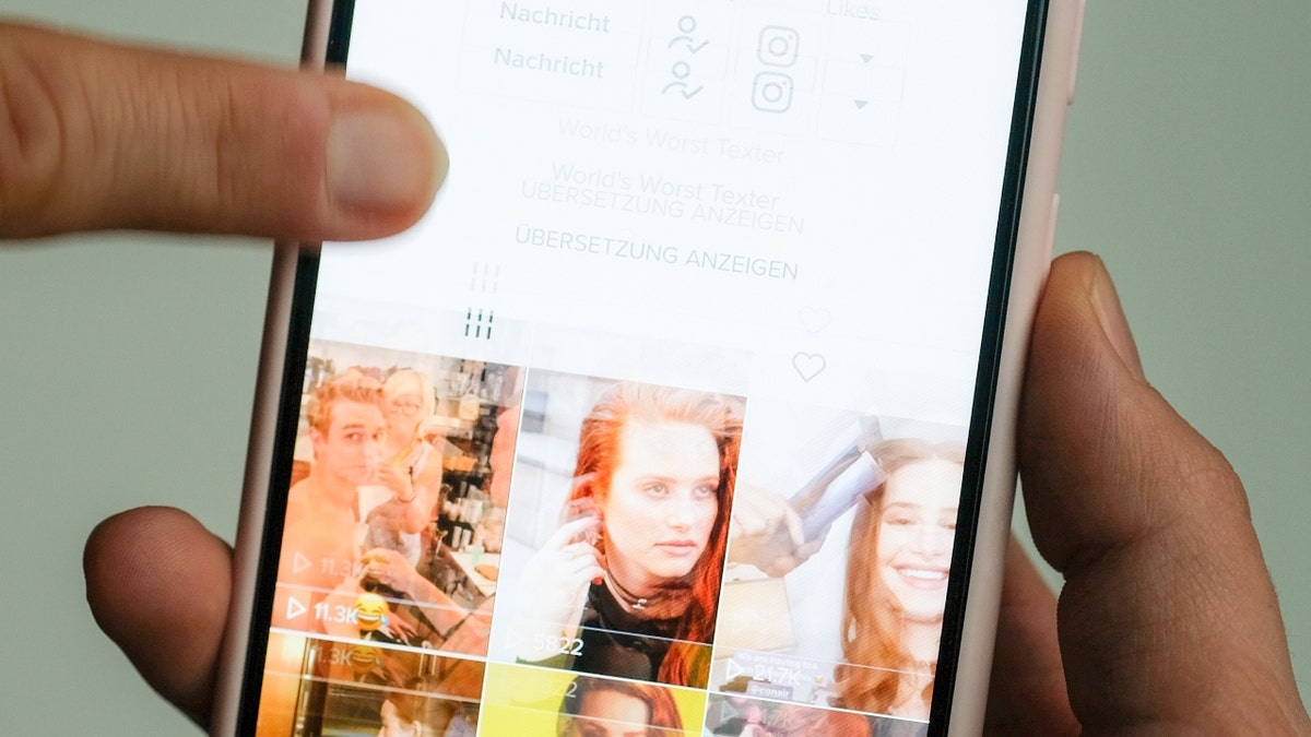 A girl holds her smartphone in her hands on which she has opened @madelainepetsch's profile in the short video app TikTok.