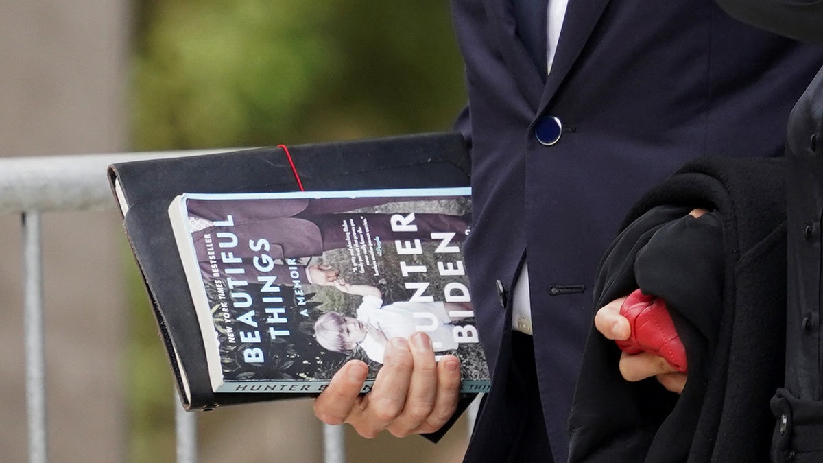 Hunter Biden holds a copy of his memoir "Beautiful Things" as he and his wife Melissa Cohen Biden depart the federal court