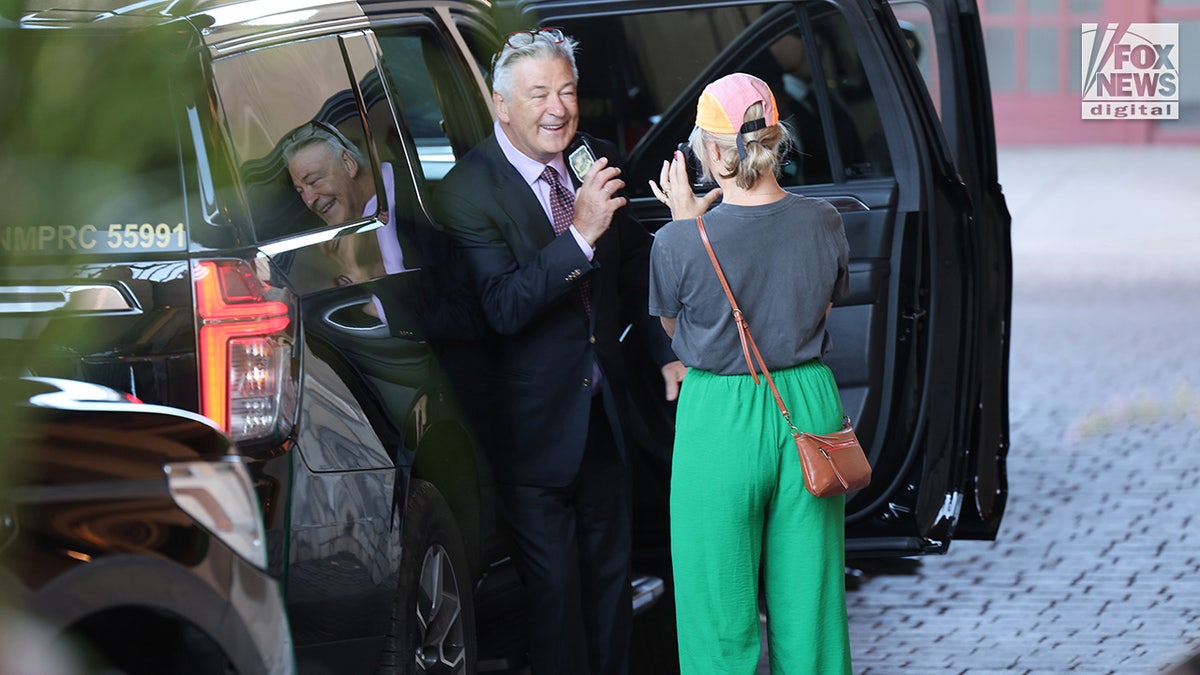 Filmmaker Jenna Rosher (R) films Alec Baldwin departing his hotel