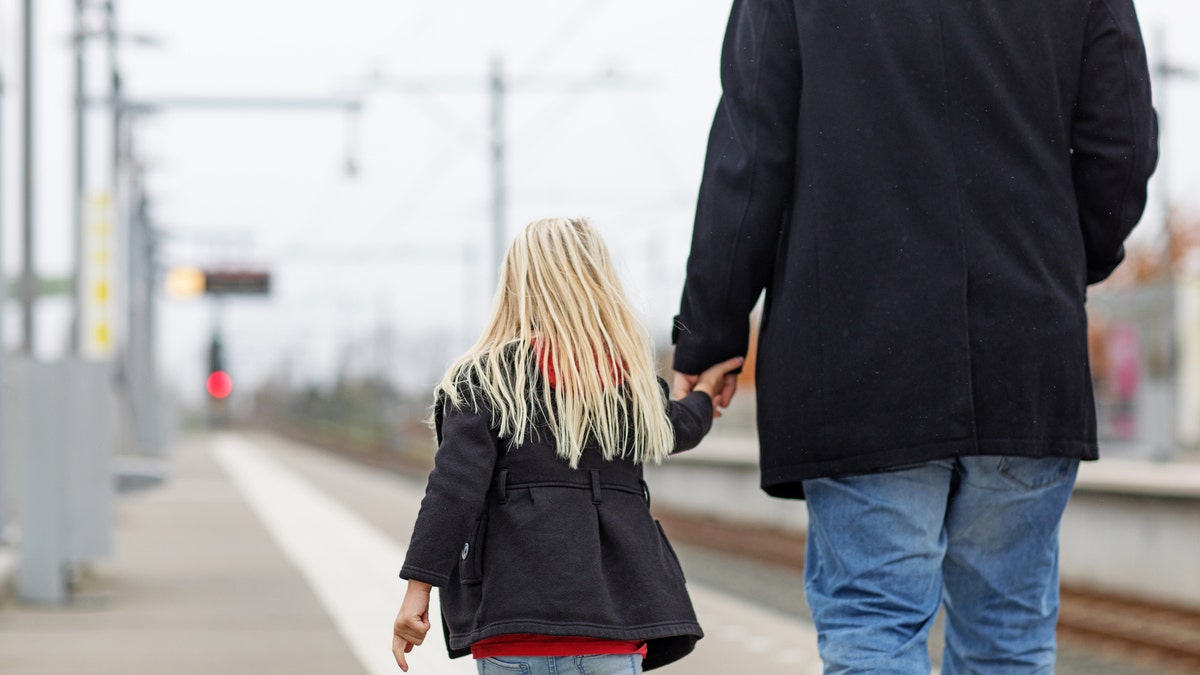 Child walking with unknown male figure