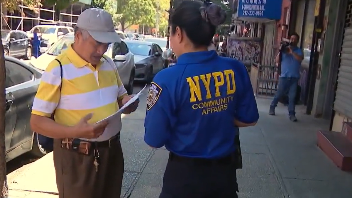 NYPD officer handing out flyers to resident