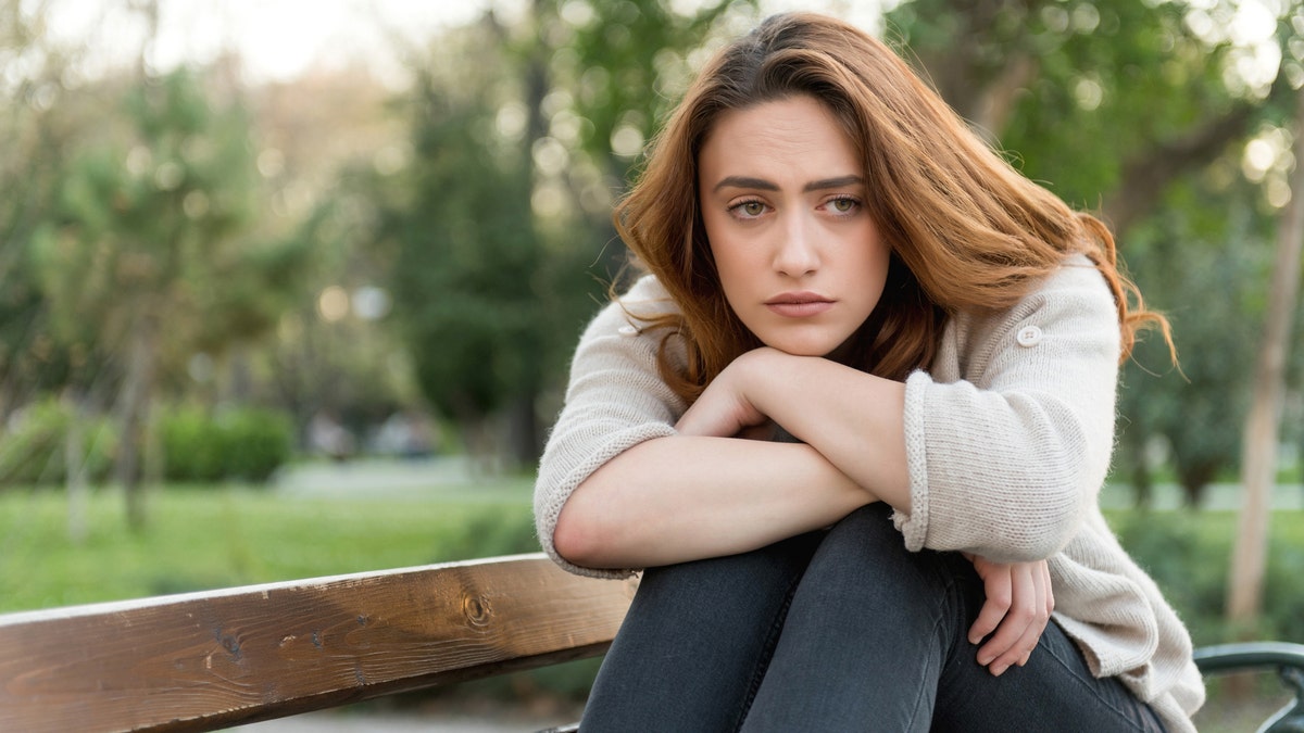 A sad woman sitting on a bench outside