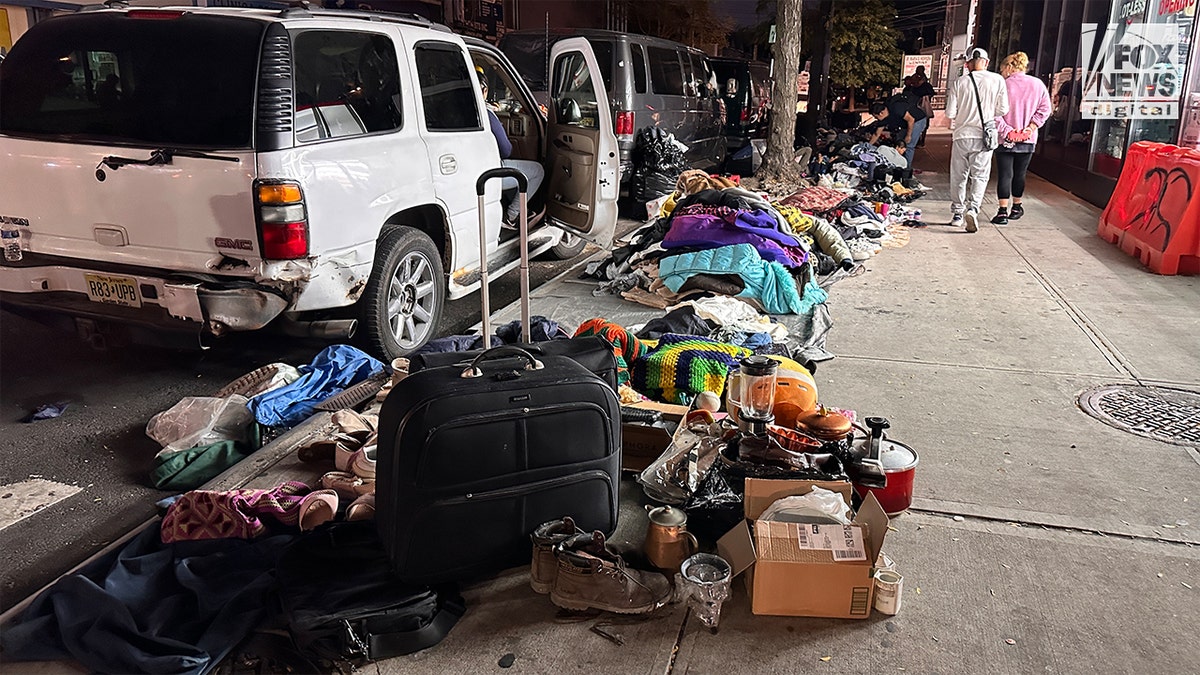 Used clothes and other used items for sale along a clogged sidewalk