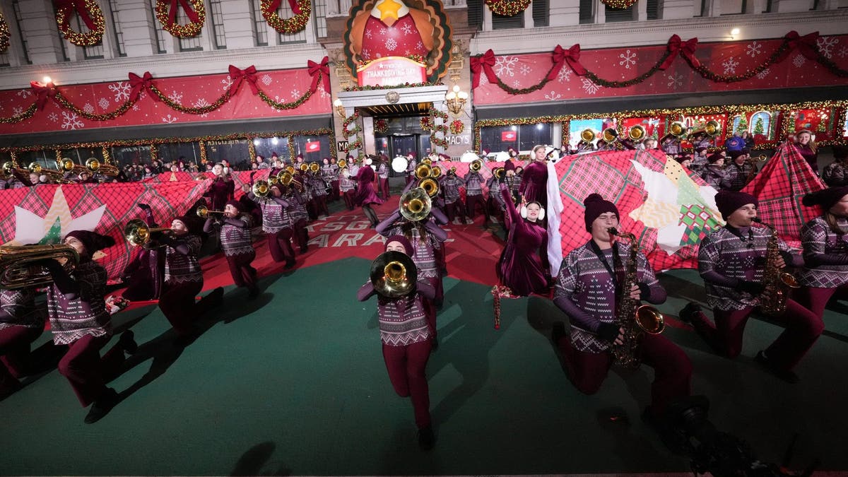 High school students in matching sweaters and red pants practice for the Macy's Thanksgiving day parade