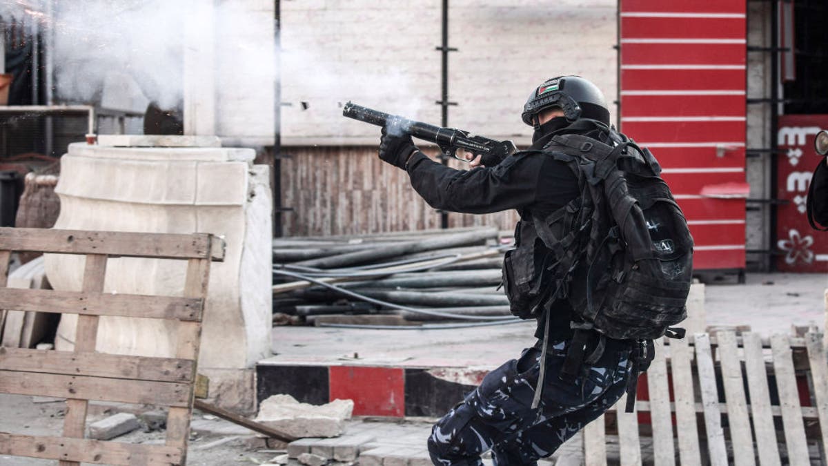 A Palestinian security man fires tear gas at protesters in the center of the West Bank city of Jenin and its camp on Dec. 16, 2024.