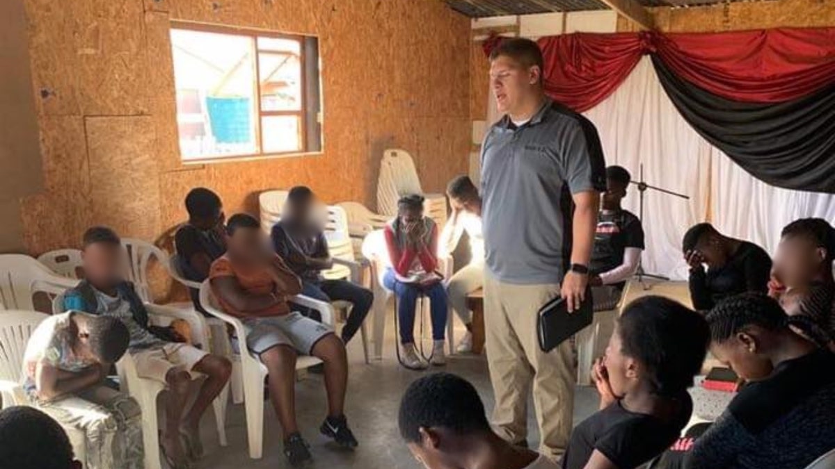 Josh Sullivan prays with a group of South African children