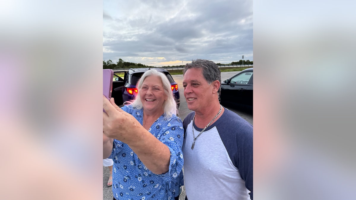 Crissie and Leo Schofield taking a selfie in a parking lot.