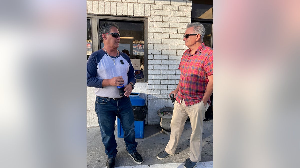 Gilbert King speaking with Leo Schofield as they both wear casual clothes.