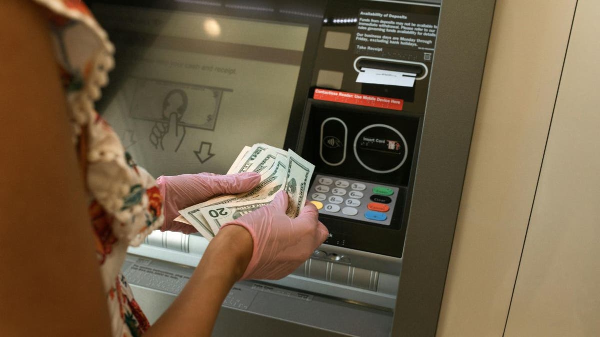 A person takes out money from an ATM