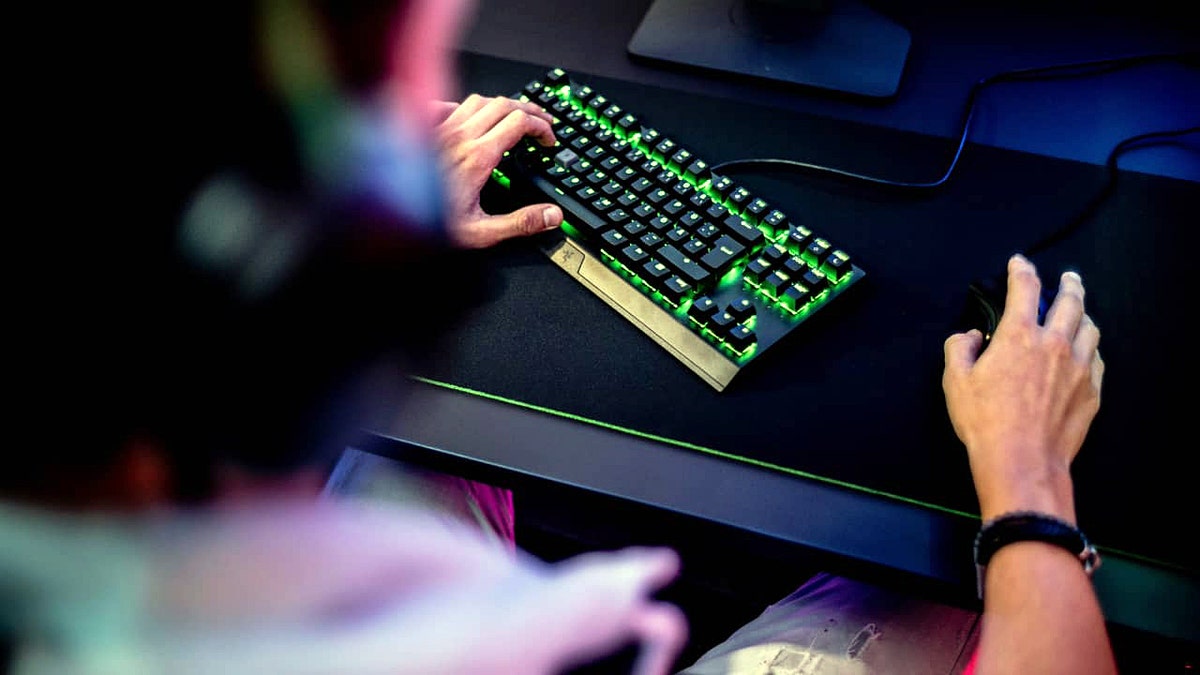 A man typing on a gaming keyboard