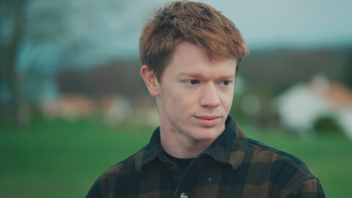 Tyler VanScyoc looking pensive outdoors wearing a plaid shirt.