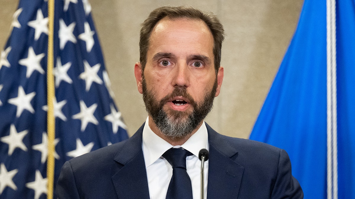 Jack Smith in front of flags.