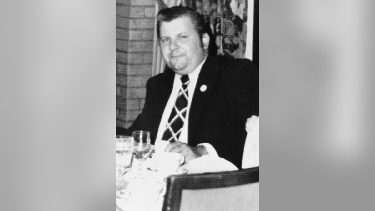 John Wayne Gacy in a suit and striped tie.
