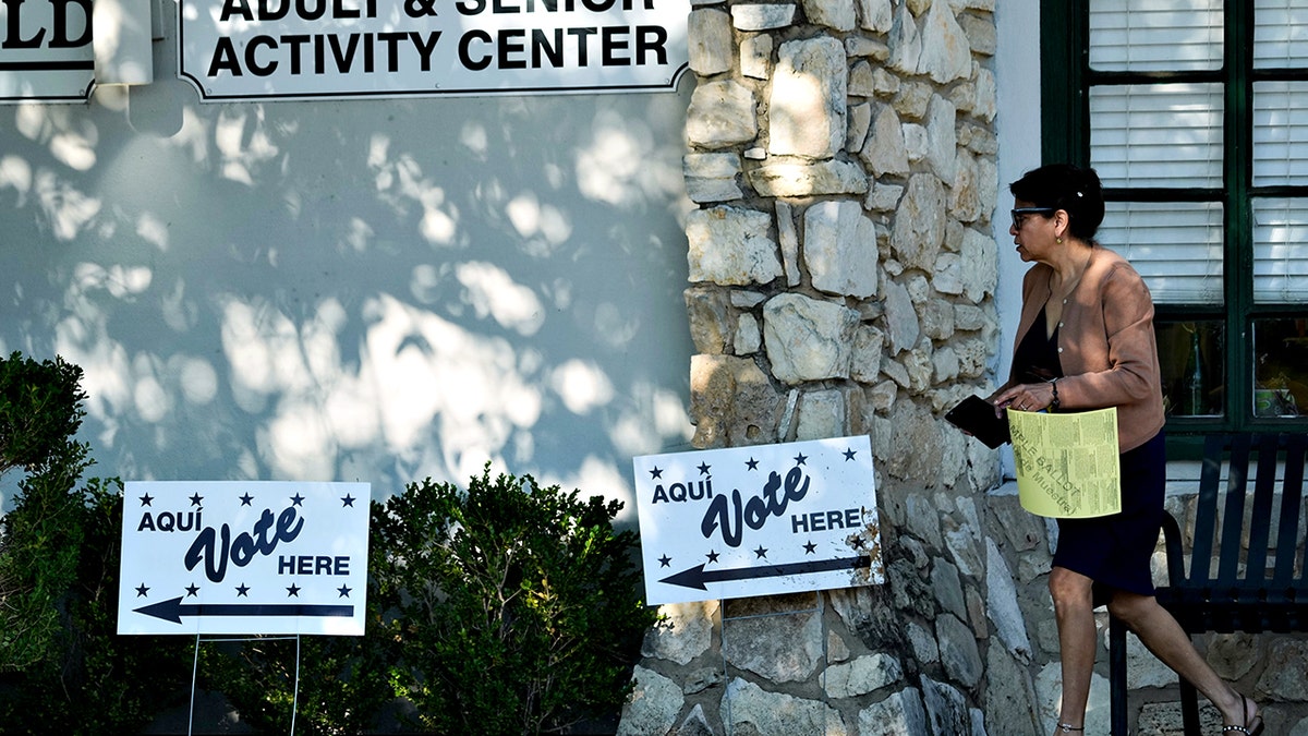 A woman carries a sample ballot into a polling station