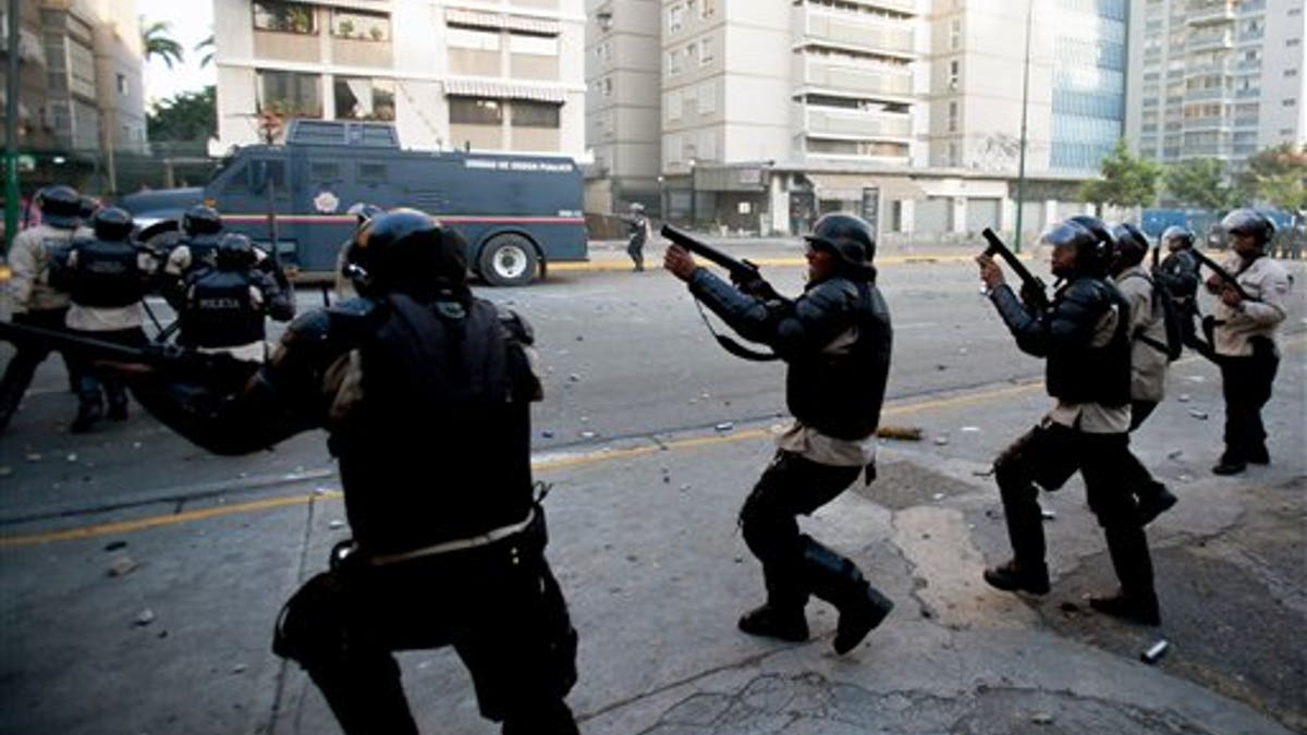 Bolivarian National Police fire tear gas toward opposition demonstrators in Caracas, Venezuela, Saturday, Feb. 15, 2014. Venezuelan security forces backed by water tanks and tear gas dispersed groups of anti-government demonstrators who tried to block Caracas' main highway Saturday evening. (AP Photo/Alejandro Cegarra)