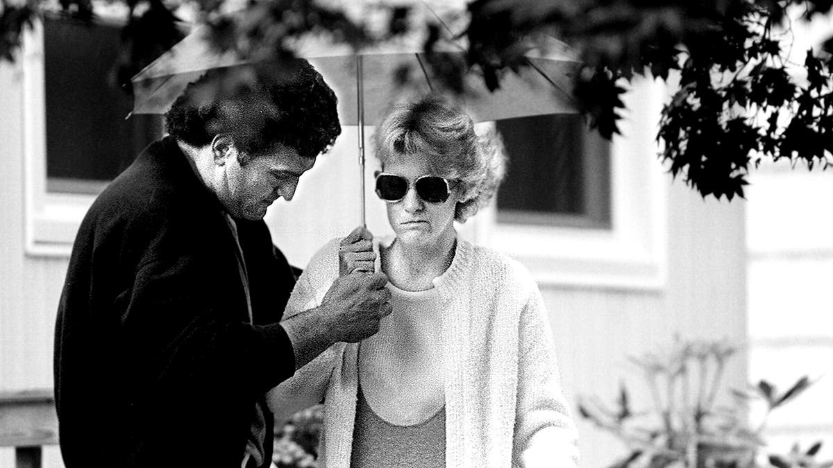 Joey Buttafuoco holding an umbrella for Mary Jo Buttafuoco.