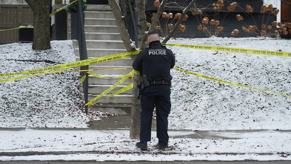 A Columbus police officer adjusts crime scene tape after officers responded to the home of Monique Tepe and Spencer Tepe