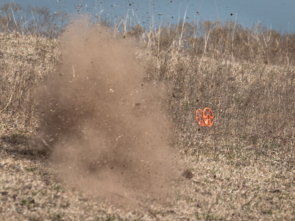 A puff of dirt exploding next to two Caldwell ClayCopter clays.