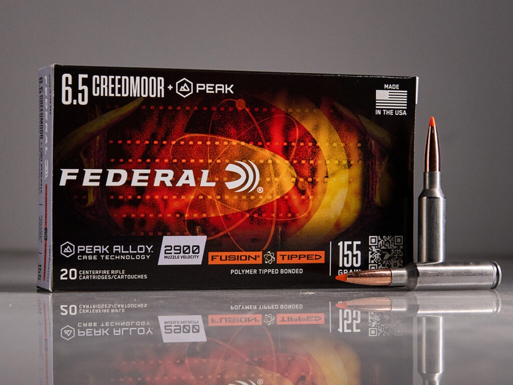 A box of Federal 6.5 Creedmoor +Peak Fusion Tipped ammo next to two loose cartridges.