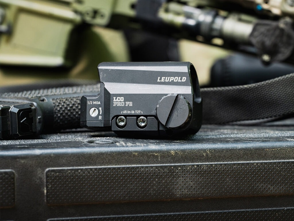 The Leupold LCO Pro F2 red dot laying on a truck bed next to a pistol.